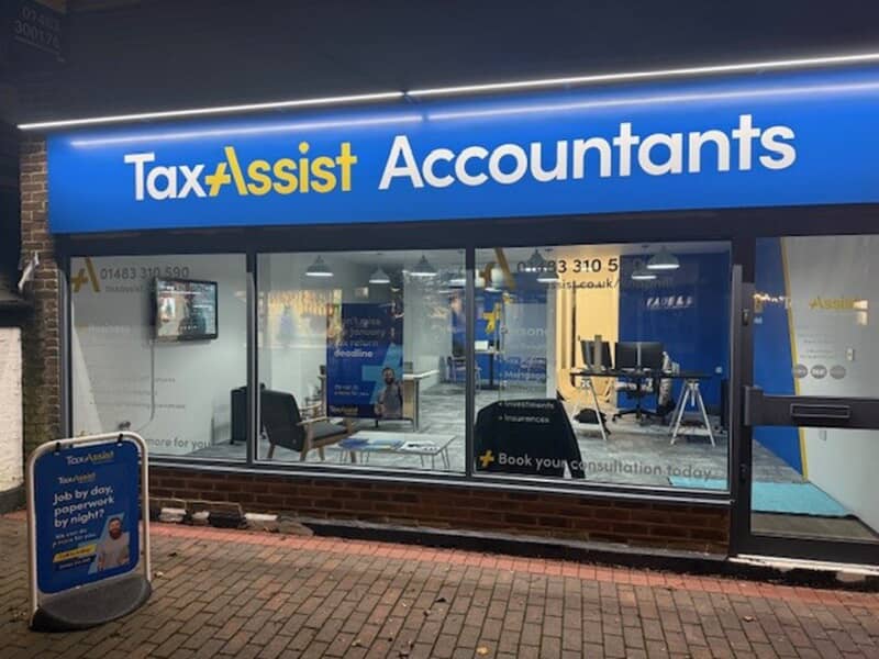 An image of a TaxAssist storefront at night while it's lit up.